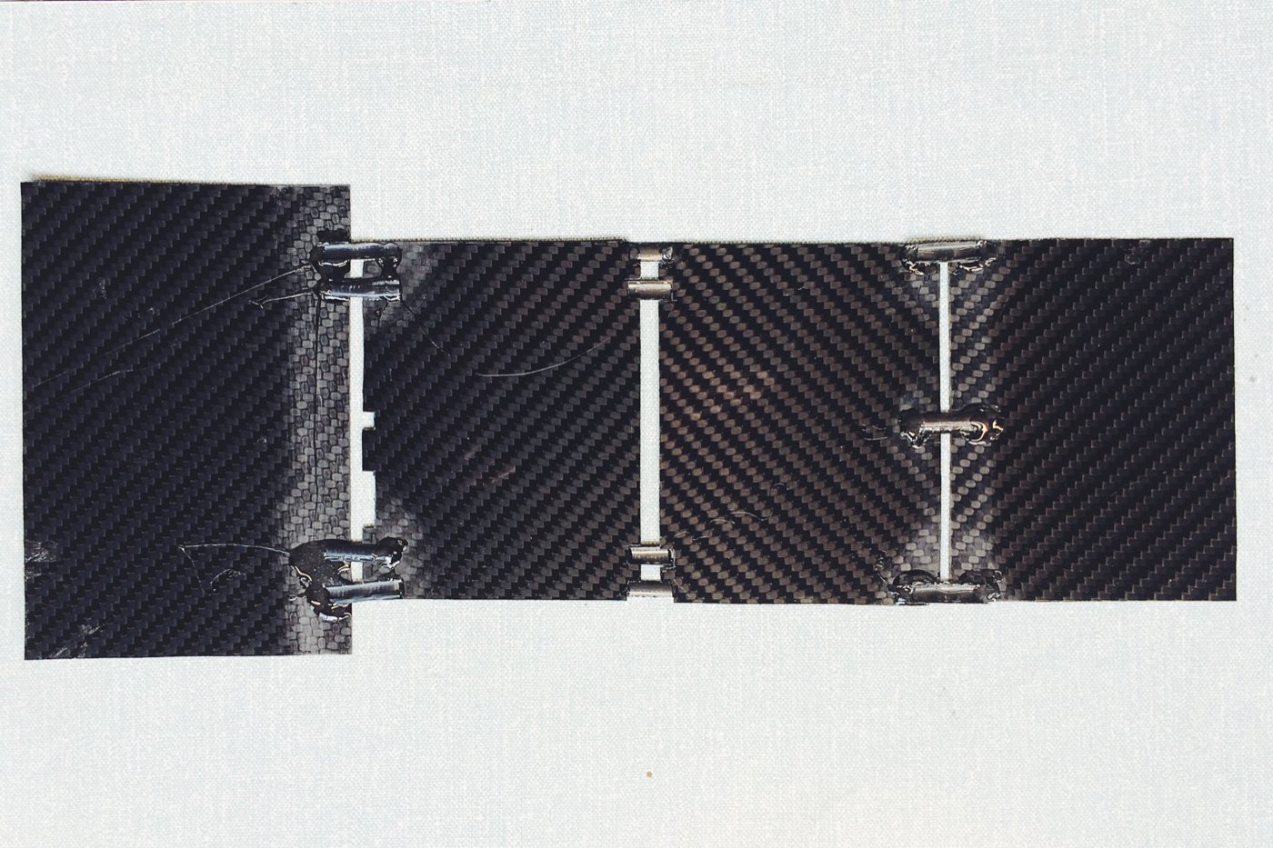 Hinged carbon-fibre satellite cells laid flat on a linen background